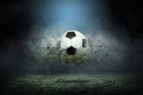 Fototapeta Poruszająca się piłka nożna wokół kropli rozchlapać na polu stadionu.